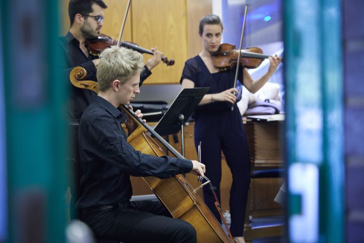 Strings chamber musicians in a practice room, preparing for a performance